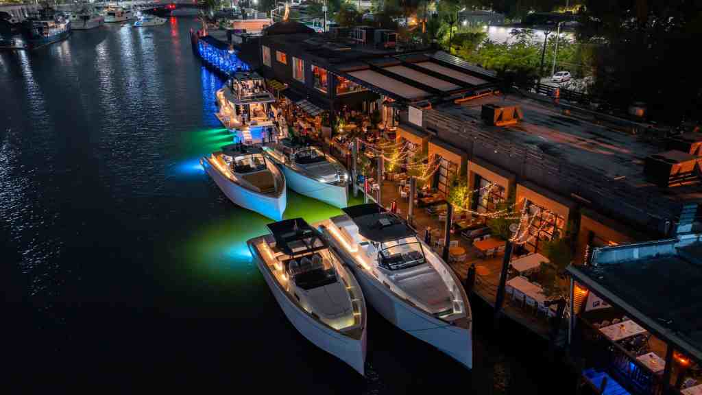 Luxury yachts docked at Pardo Yachts Miami marina at night with vibrant lighting.