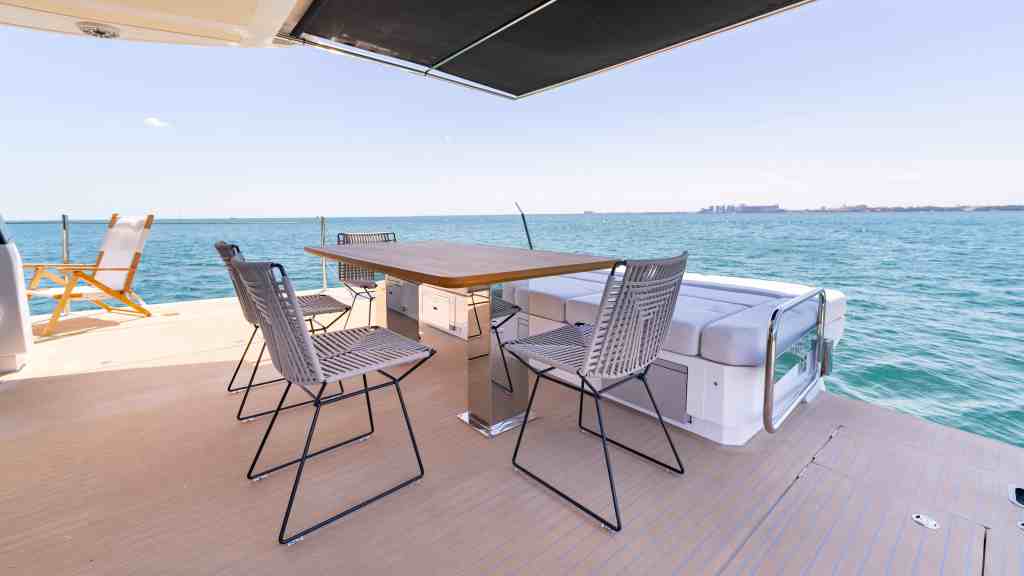 Luxury yacht deck with dining table and chairs overlooking the ocean.